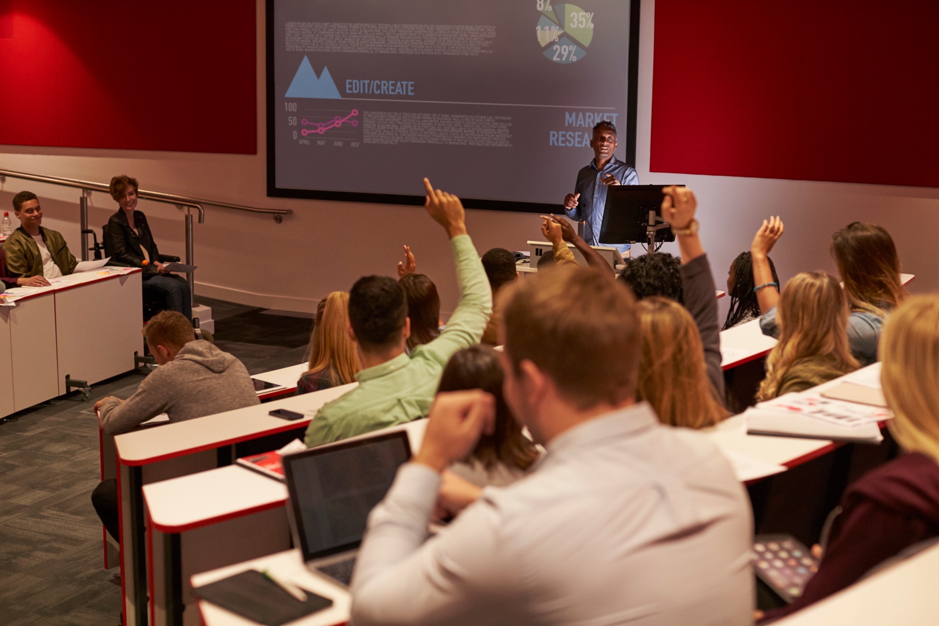 Students raising their hands in a university lecture hall