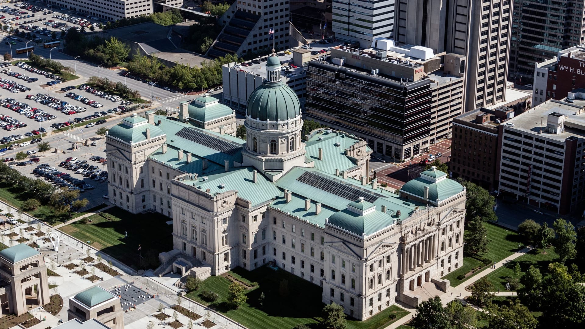 Aerial view of a state capitol building rising above a major-city downtown skyline