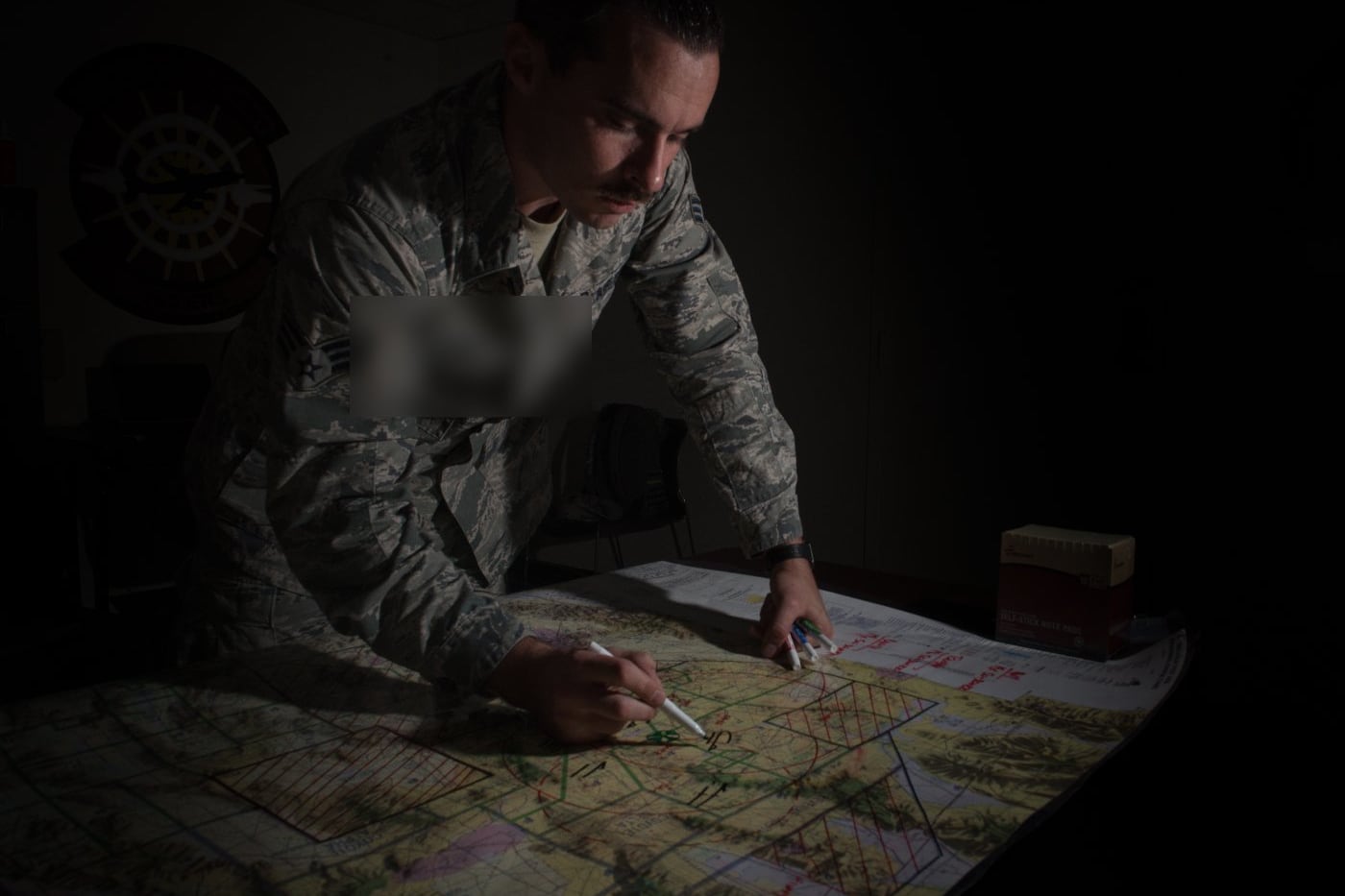 An Air Force analyst annotating a classified operations map inside a secure facility