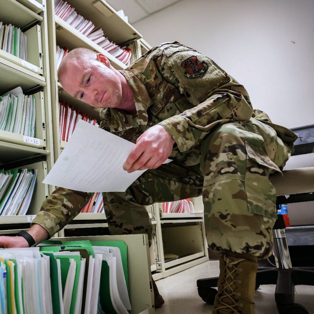 A U.S. Air Force airman retrieving paper records from a filing system